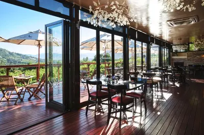a restaurant with tables and chairs on a deck at Alluvia Boutique Winery & Luxury Accommodation in Stellenbosch