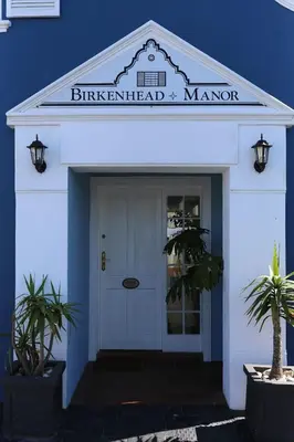 a blue and white building with a white door at Birkenhead Manor in Bloubergstrand
