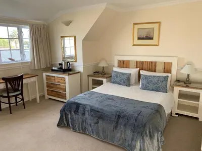 a bedroom with a bed and a desk and a chair at Birkenhead Manor in Bloubergstrand
