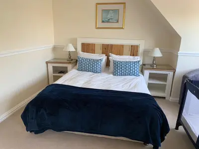 a bedroom with a large bed with blue and white pillows at Birkenhead Manor in Bloubergstrand
