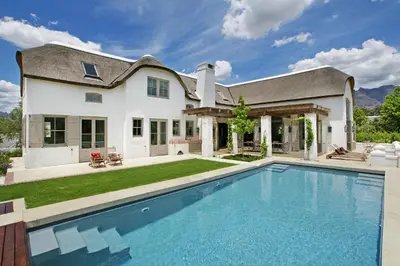 a home with a swimming pool in front of a house at Villa Simondium in Franschhoek