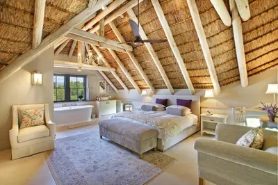 a bedroom with a bed and a couch and a chair at Villa Simondium in Franschhoek