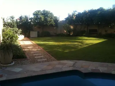 a backyard with a yard with a pool and grass at Roman Retreat in Cape Town