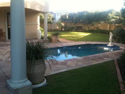 a swimming pool in a yard next to a house at Roman Retreat in Cape Town