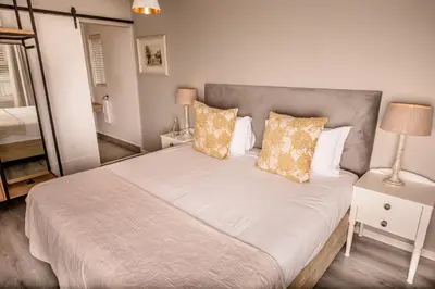 a bedroom with a large bed with white sheets and pillows at The Corner House L'A-nnexe in Franschhoek