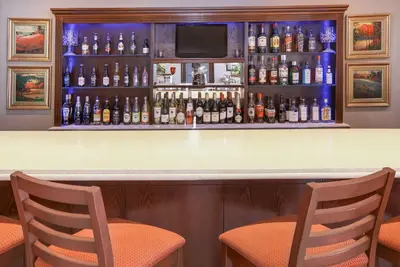 a bar with two chairs and bottles of alcohol at StayEasy Century City in Cape Town