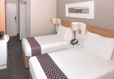 a hotel room with two beds and a telephone at StayEasy Century City in Cape Town