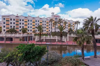 a large building with palm trees in front of a river at StayEasy Century City in Cape Town