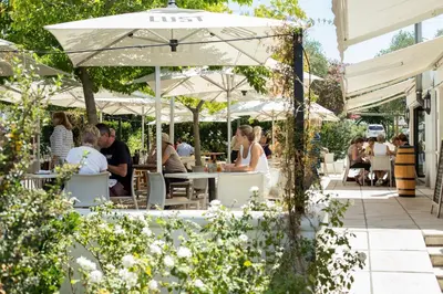 people sitting at tables under umbrellas at a restaurant at Vrede en Lust Estate in Simondium