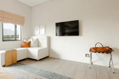 a white living room with a white couch and a tv at Vrede en Lust Estate in Simondium