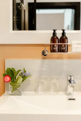 a bathroom sink with a flower in a vase on it at Vrede en Lust Estate in Simondium