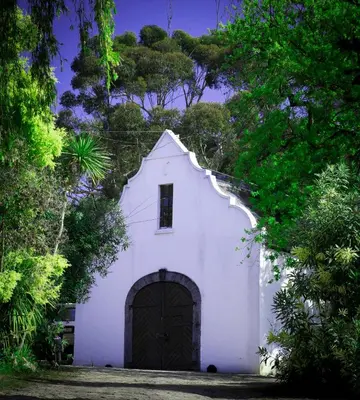 a small white church with a door and trees at Mooiplaas Wine Estate in Stellenbosch