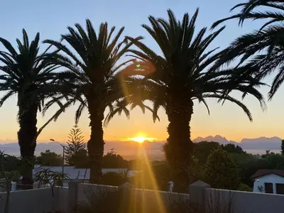 a sunset from the roof of a house with palm trees at Four Palms Accommodation in Durbanville