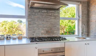 a kitchen with a stove top oven next to a window at Pringle Bay Home in Pringle Bay