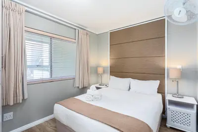 a bedroom with a large white bed and a window at Lagoon Beach 237A by CTHA in Cape Town