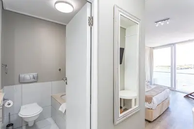 a bathroom with a toilet and a sink and a mirror at Lagoon Beach 237A by CTHA in Cape Town
