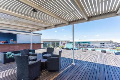a deck with chairs and a table with a view of a boat at Lagoon Beach 237A by CTHA in Cape Town
