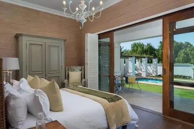a bedroom with a bed and a patio with a pool at The Residence @ Vrede & Lust in Franschhoek