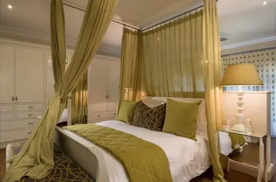 a bedroom with a canopy bed with green pillows at The Residence @ Vrede & Lust in Franschhoek