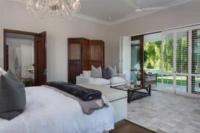 a bedroom with two beds and a living room with a chandelier at The Residence @ Vrede & Lust in Franschhoek