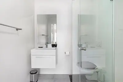 a white bathroom with a sink and a shower at The Paragon 317 in Cape Town