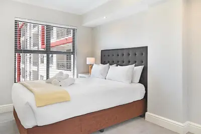 a bedroom with a large white bed with a window at The Paragon 317 in Cape Town