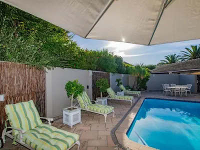 a patio with chairs and a swimming pool at Eikelower Accommodation in Stellenbosch