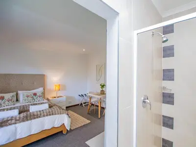 a bedroom with a king sized bed and a shower at Eikelower Accommodation in Stellenbosch