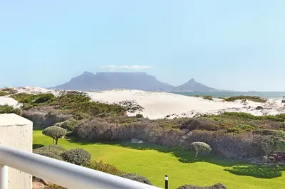 a view of a sandy beach with trees and grass at Dolphin Beach E5 in Bloubergstrand