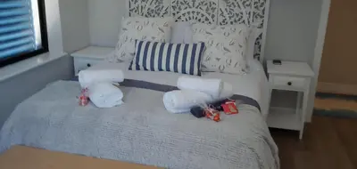a bedroom with a bed with white sheets and pillows at The Sun, Whales & Waves - Seafront Apartment in Hermanus