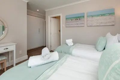 a bedroom with two beds and a fireplace at The Sun, Whales & Waves - Seafront Apartment in Hermanus