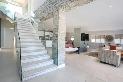 a staircase in a living room with a stone wall at 269 on Main Holiday Home in Hermanus