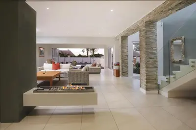 a living room with a fireplace in the middle at 269 on Main Holiday Home in Hermanus