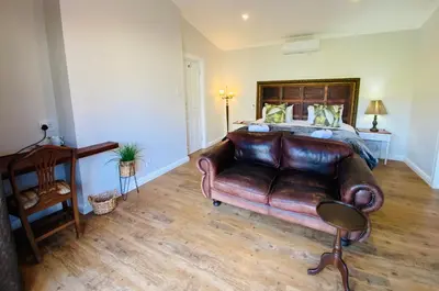 a bedroom with a leather bed and a leather couch at Goblin's Mead in Edgemead