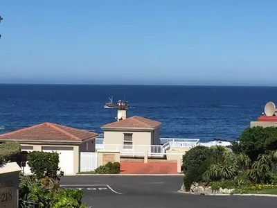 a house with a lighthouse in front of the ocean at 155 hbc in Hermanus