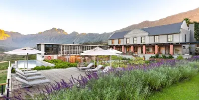 a hotel with chairs and umbrellas in a garden at De Zeven Guest Lodge in Stellenbosch