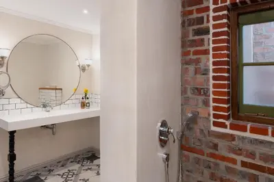 a bathroom with a sink and a mirror and a brick wall at De Zeven Guest Lodge in Stellenbosch