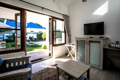 a living room with a tv and a table at Sixteen Guesthouse on Main in Hermanus