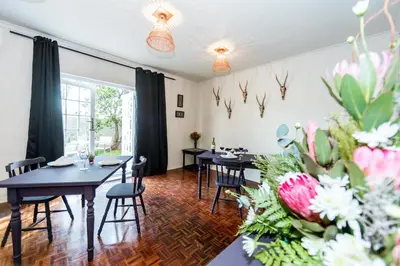 a dining room with tables and chairs and flowers at Le Petit Chateau Guest House in Durbanville