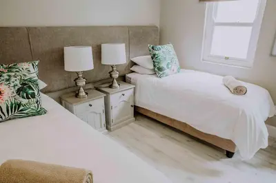 a bedroom with two beds and two lamps and a window at Franschhoek Village House in Franschhoek