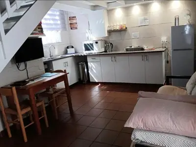 a kitchen with white cabinets and a table and a counter at Dawn's Place in Strand