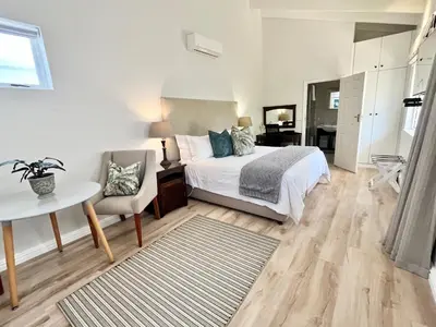 a bedroom with a bed and a table and a chair at Oakvale Lodge in Cape Town