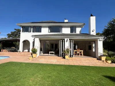 a white house with a patio and a yard at Oakvale Lodge in Cape Town
