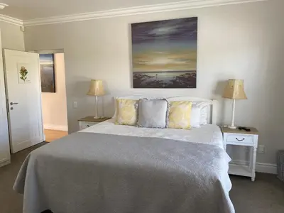 a bedroom with a bed and two lamps and a painting at Shore's Edge Luxury Oceanfront Home in Hermanus