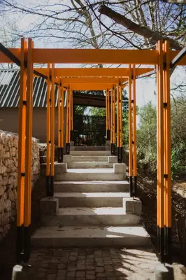 an entrance to a shrine with orange poles at Southern Yurts in Botrivier