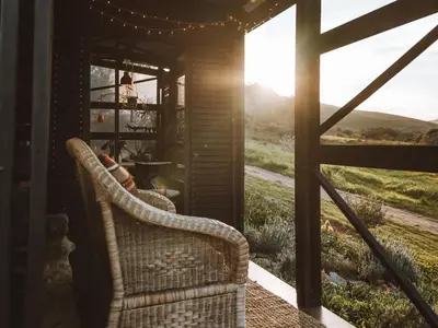 a wicker chair sitting on a porch with a view of a field at Southern Yurts in Botrivier