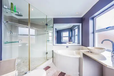 a bathroom with a tub and a sink and a shower at Gaia Hydro-Spa and Guest House in Cape Town