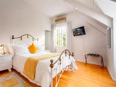 a white bedroom with a bed and a window at Cosimi Guest House in Durbanville
