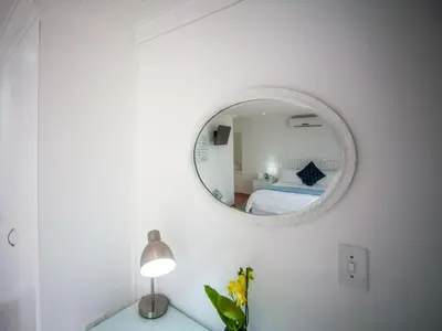 a white room with a mirror and a bed at Cosimi Guest House in Durbanville