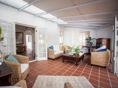 a living room with wicker chairs and a table at Cosimi Guest House in Durbanville